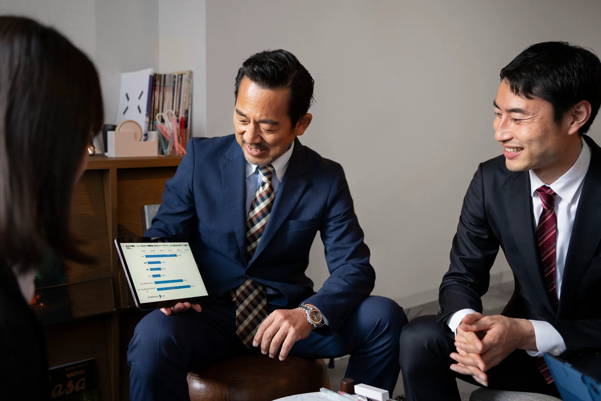 ผู้บริหารใส่สูทพูดคุยและพิจารณาข้อมูลธุรกิจร่วมกัน